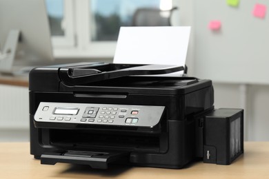 Modern printer with paper on wooden table in office