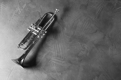 Photo of Shiny trumpet on grey textured table, top view. Space for text. Wind musical instrument