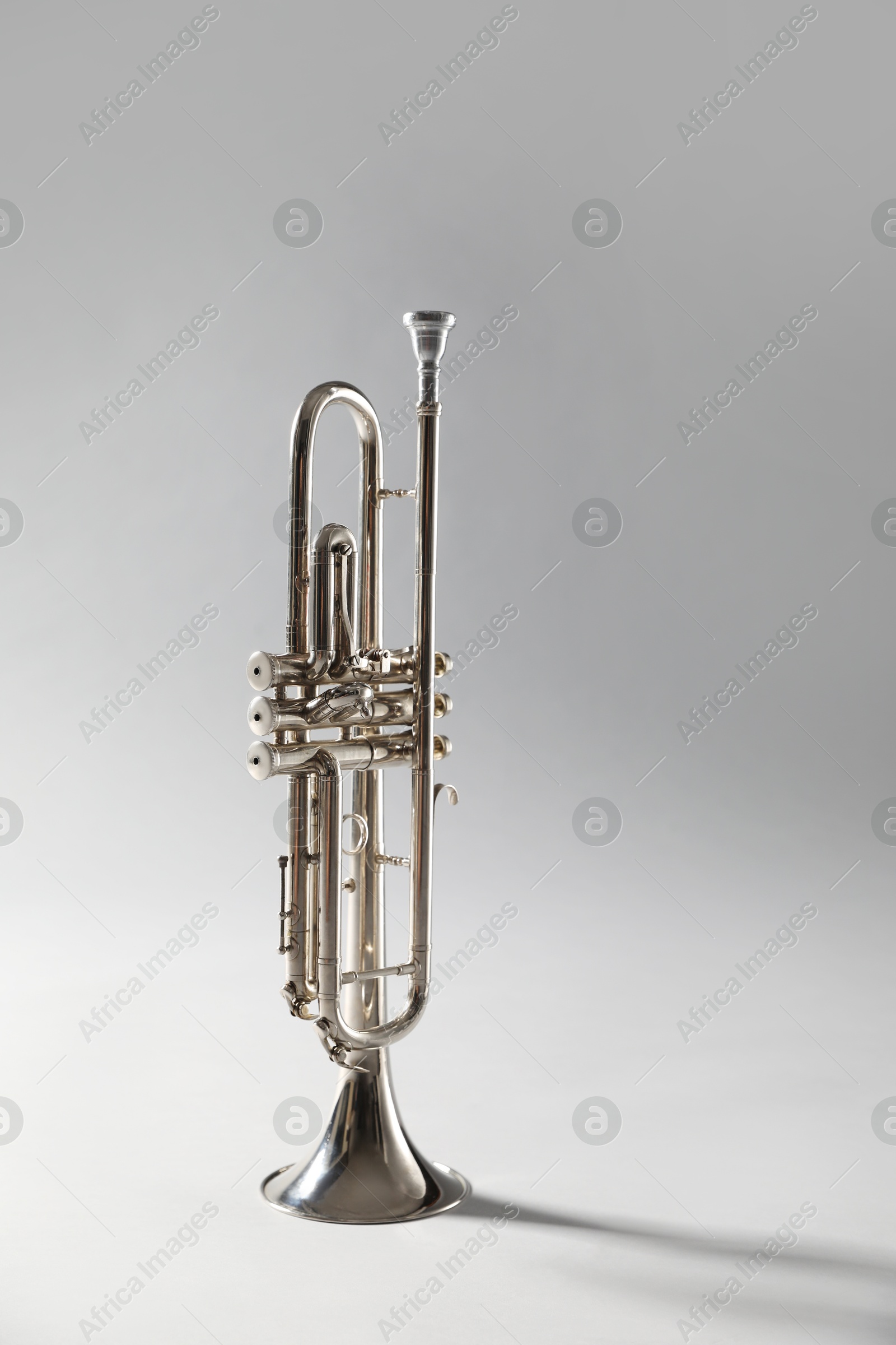 Photo of Shiny trumpet on light grey background. Wind musical instrument