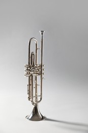 Photo of Shiny trumpet on light grey background. Wind musical instrument