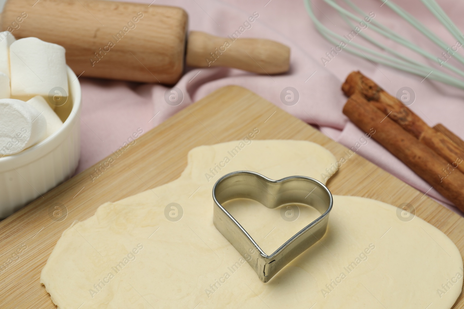 Photo of Raw dough, cookie cutter and rolling pin on table, closeup