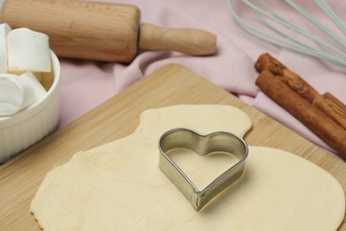 Photo of Raw dough, cookie cutter and rolling pin on table, closeup