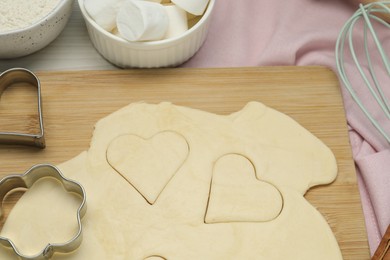 Photo of Raw dough and cookie cutters on table, closeup