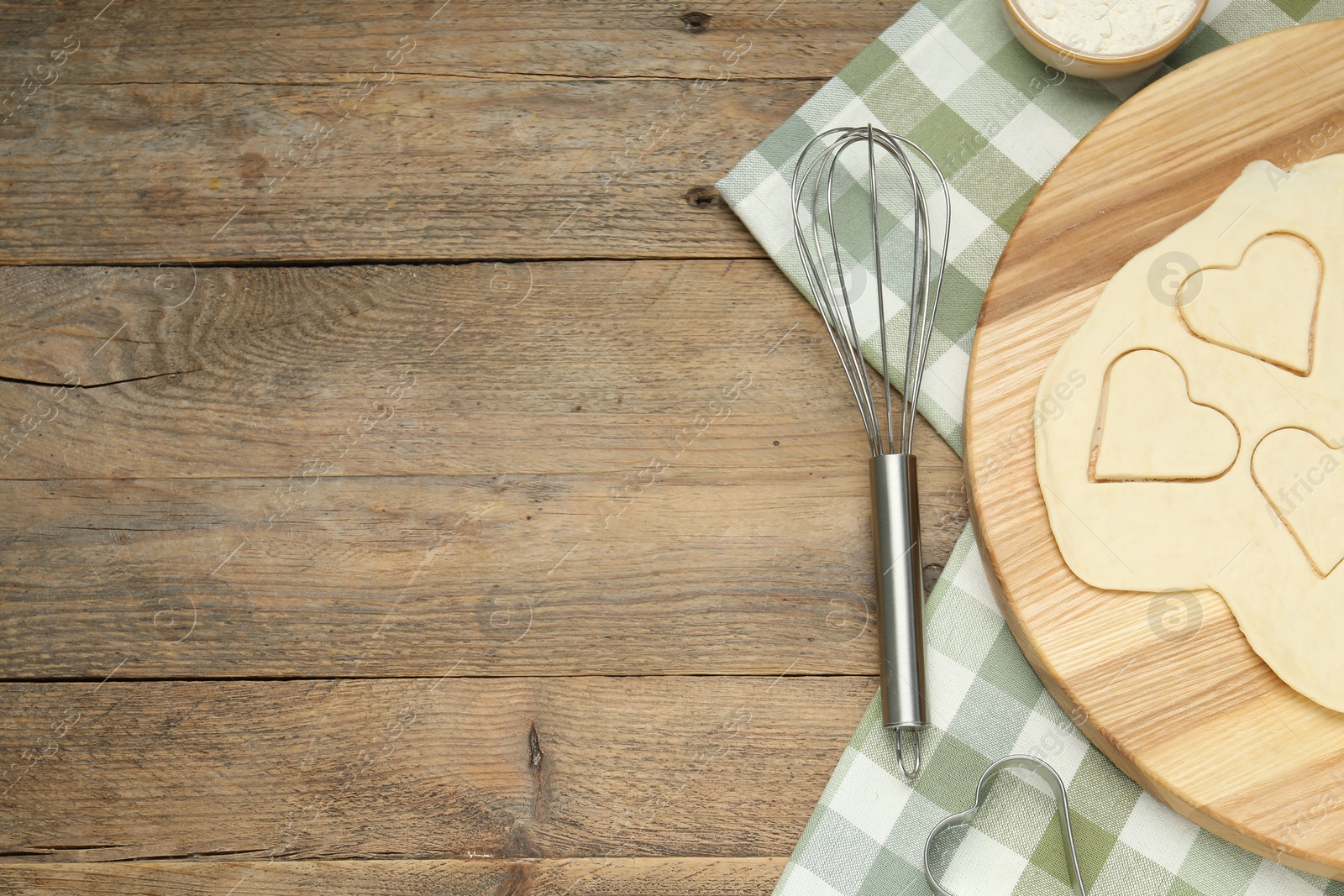 Photo of Raw dough, whisk and flour on wooden table, flat lay. Space for text