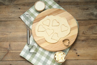 Photo of Raw dough, cookie cutter, whisk, butter and flour on wooden table, flat lay