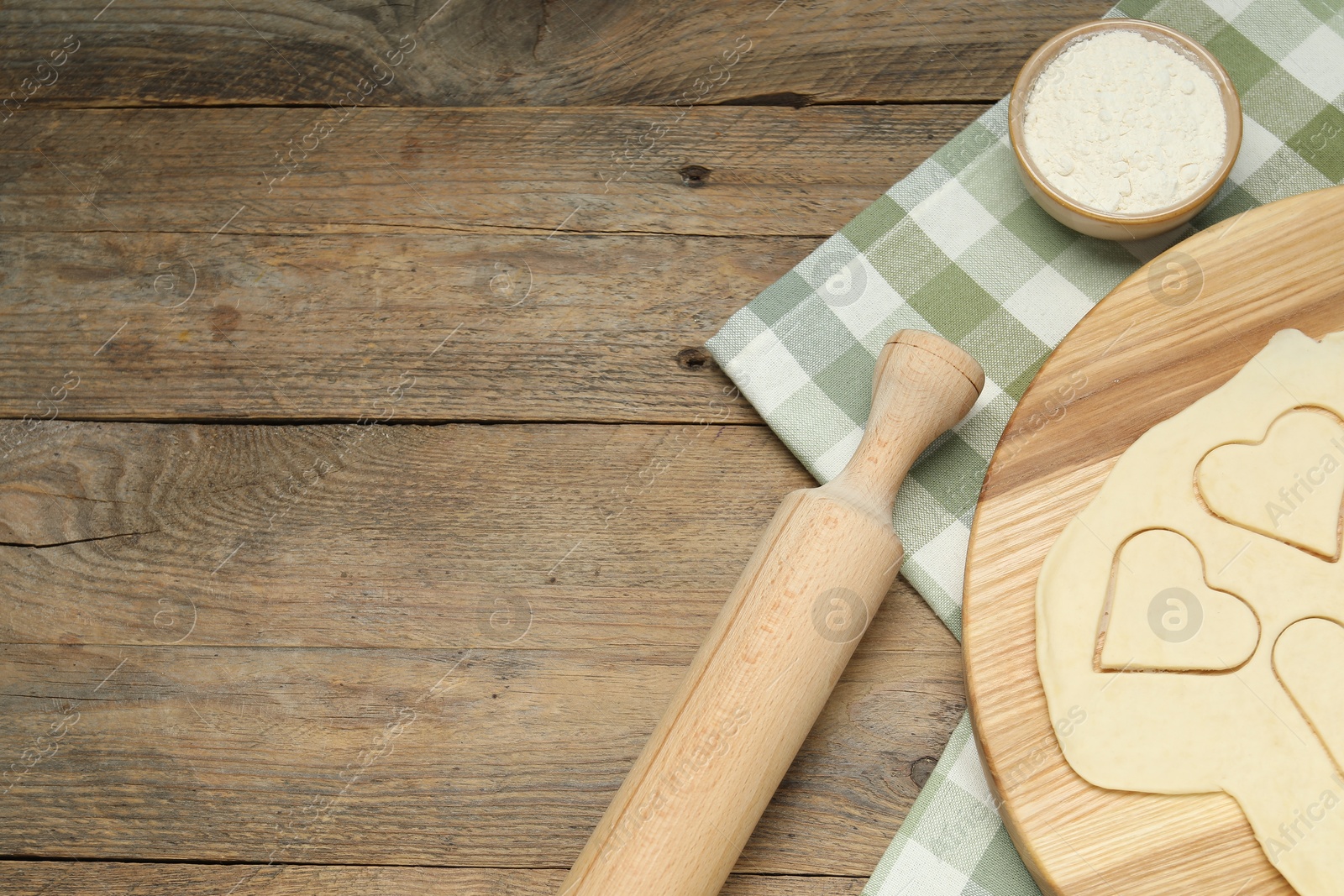 Photo of Raw dough, rolling pin and flour on wooden table, flat lay. Space for text