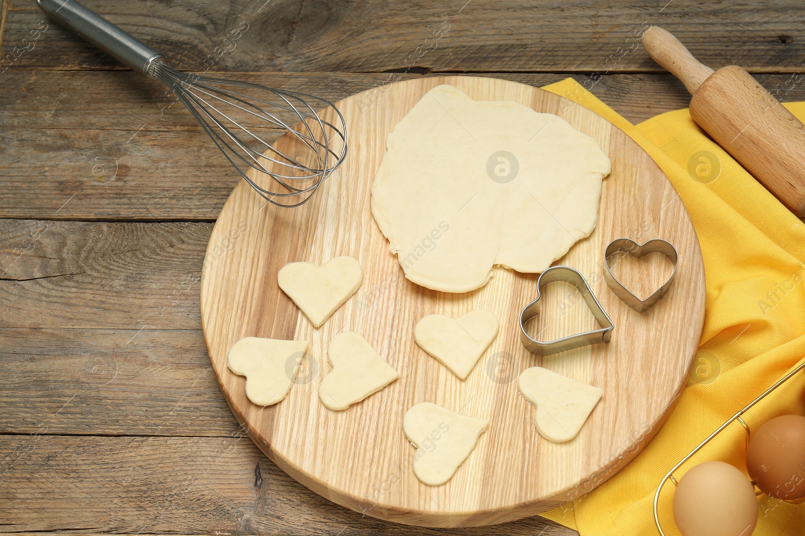 Photo of Raw dough, cookie cutters, rolling pin and eggs on wooden table, above view