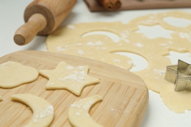 Raw dough, cookie cutter and rolling pin on white table, closeup