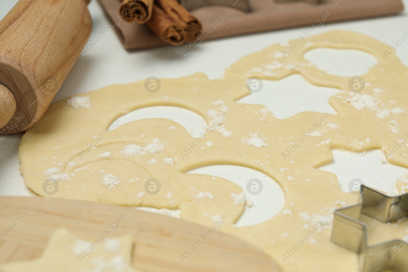 Photo of Raw dough, cookie cutter and rolling pin on white table, closeup