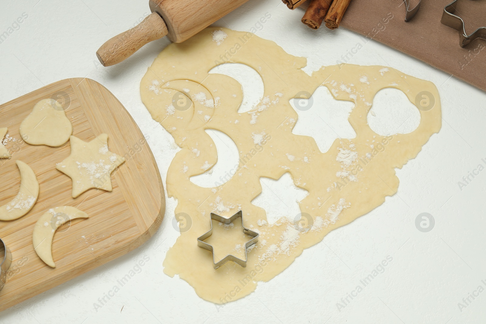 Photo of Raw dough and cookie cutters on white table, above view