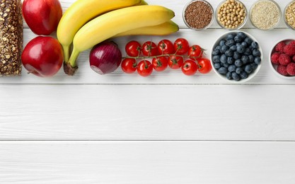 Different fresh products on white wooden table, flat lay and space for text. Source of prebiotics