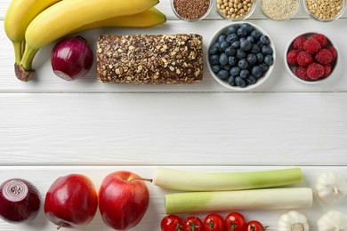 Different fresh products on white wooden table, flat lay and space for text. Source of prebiotics