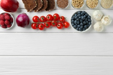 Photo of Different fresh products on white wooden table, flat lay and space for text. Source of prebiotics