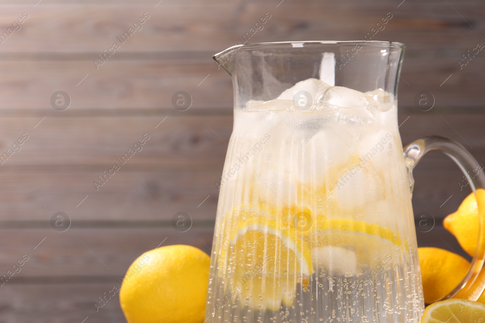 Photo of Freshly made lemonade in jug on table, closeup. Space for text