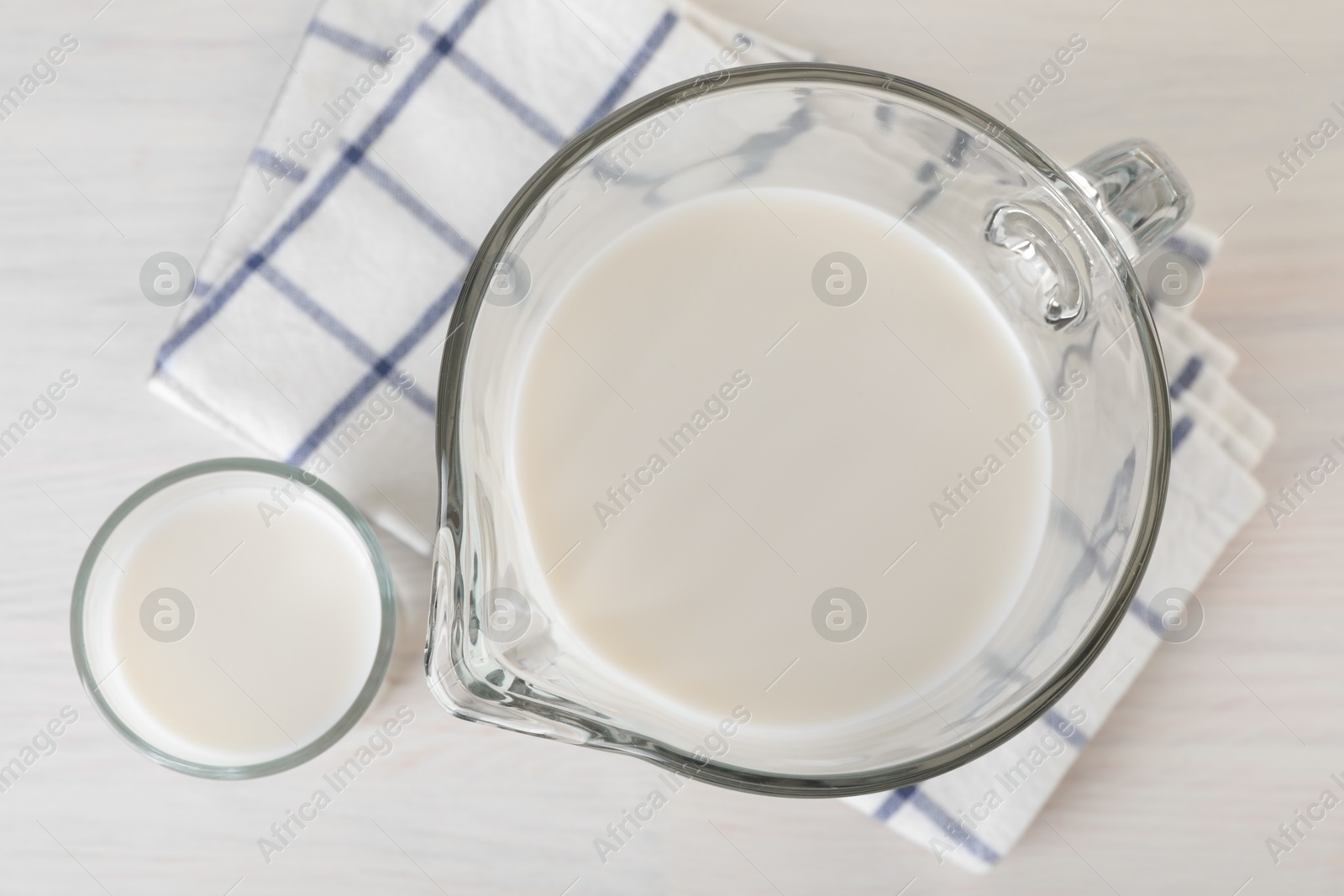 Photo of Jug and glass of fresh milk on wooden table, top view