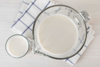 Photo of Jug and glass of fresh milk on wooden table, top view