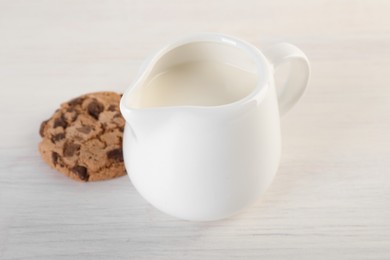 Photo of Jug of fresh milk and cookie isolated on wooden table