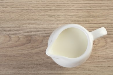 Photo of Jug of fresh milk isolated on wooden table, top view. Space for text