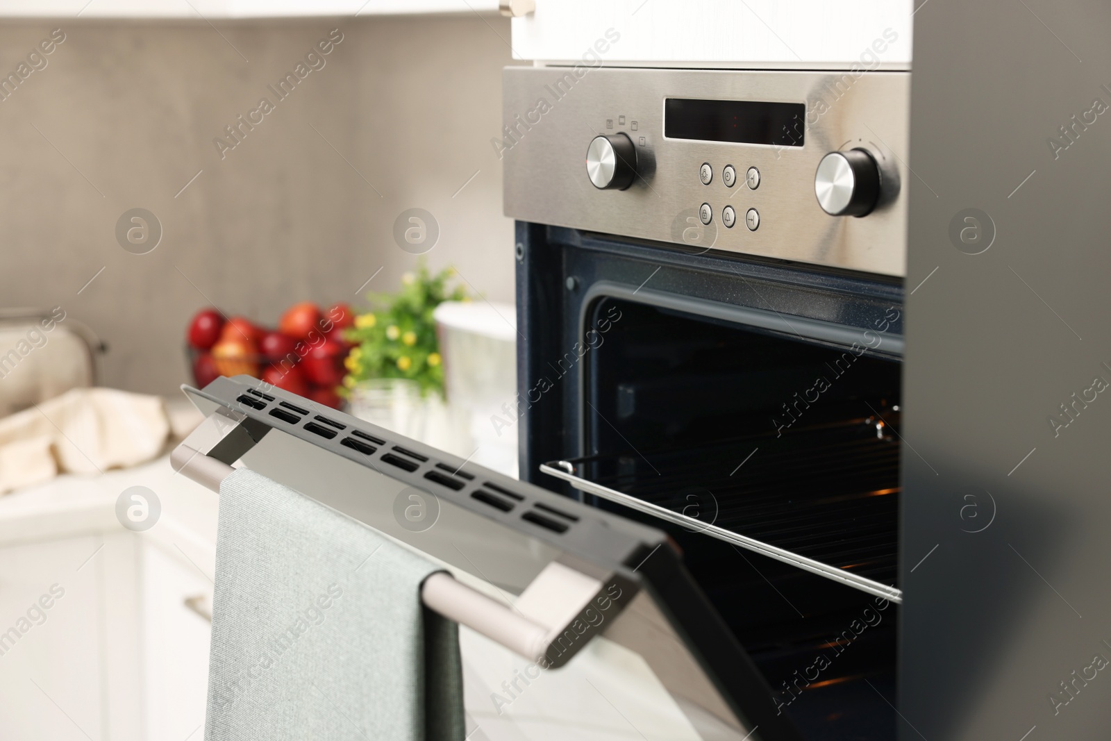 Photo of Open electric oven with towel in kitchen. Cooking appliance