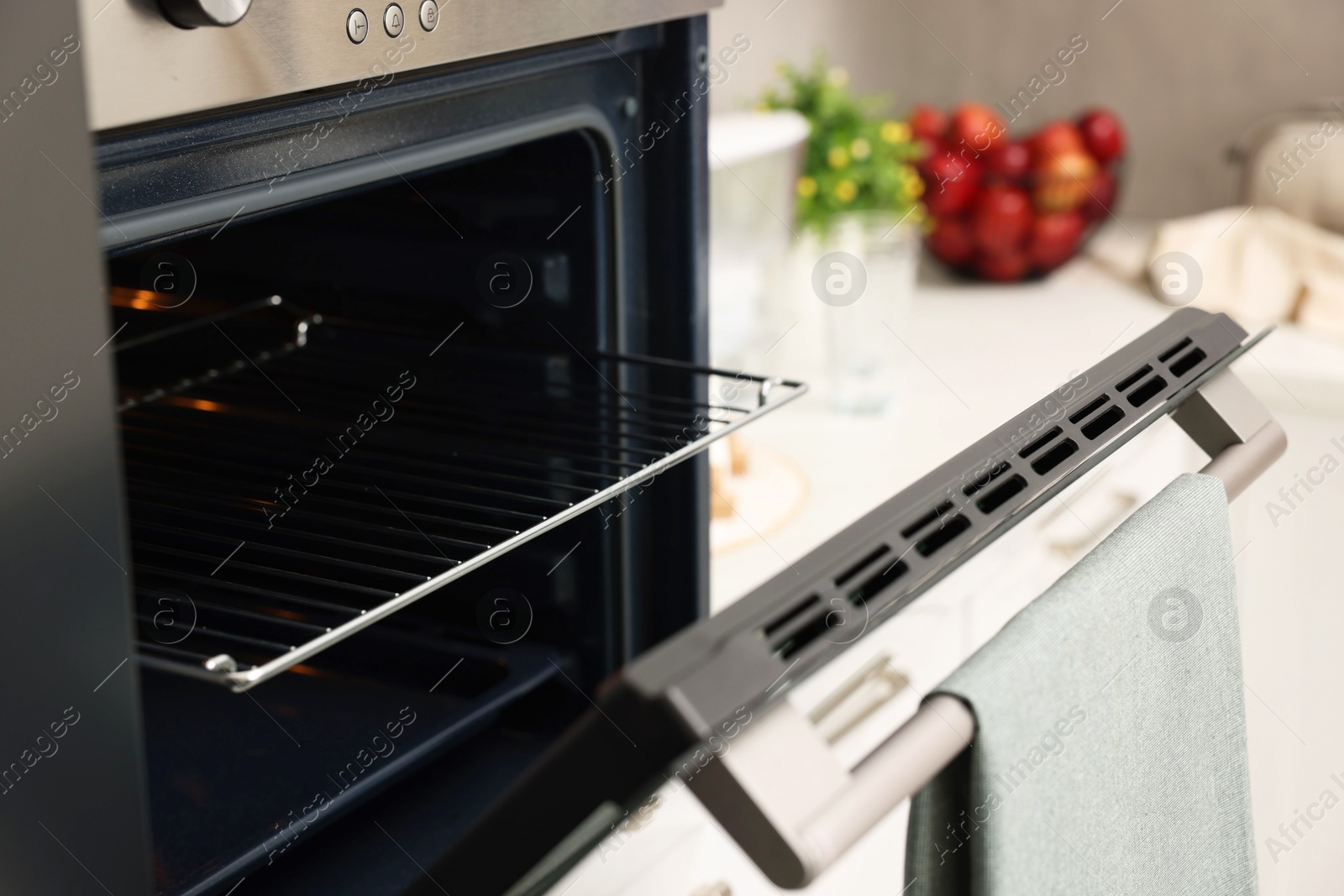 Photo of Open electric oven with towel in kitchen. Cooking appliance