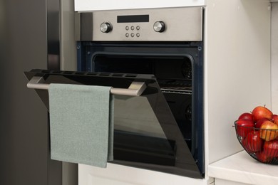 Photo of Open electric oven with towel in kitchen. Cooking appliance