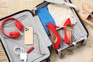 Open suitcase with traveler's belongings on floor, top view