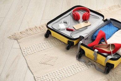 Open suitcase with traveler's belongings on floor, space for text