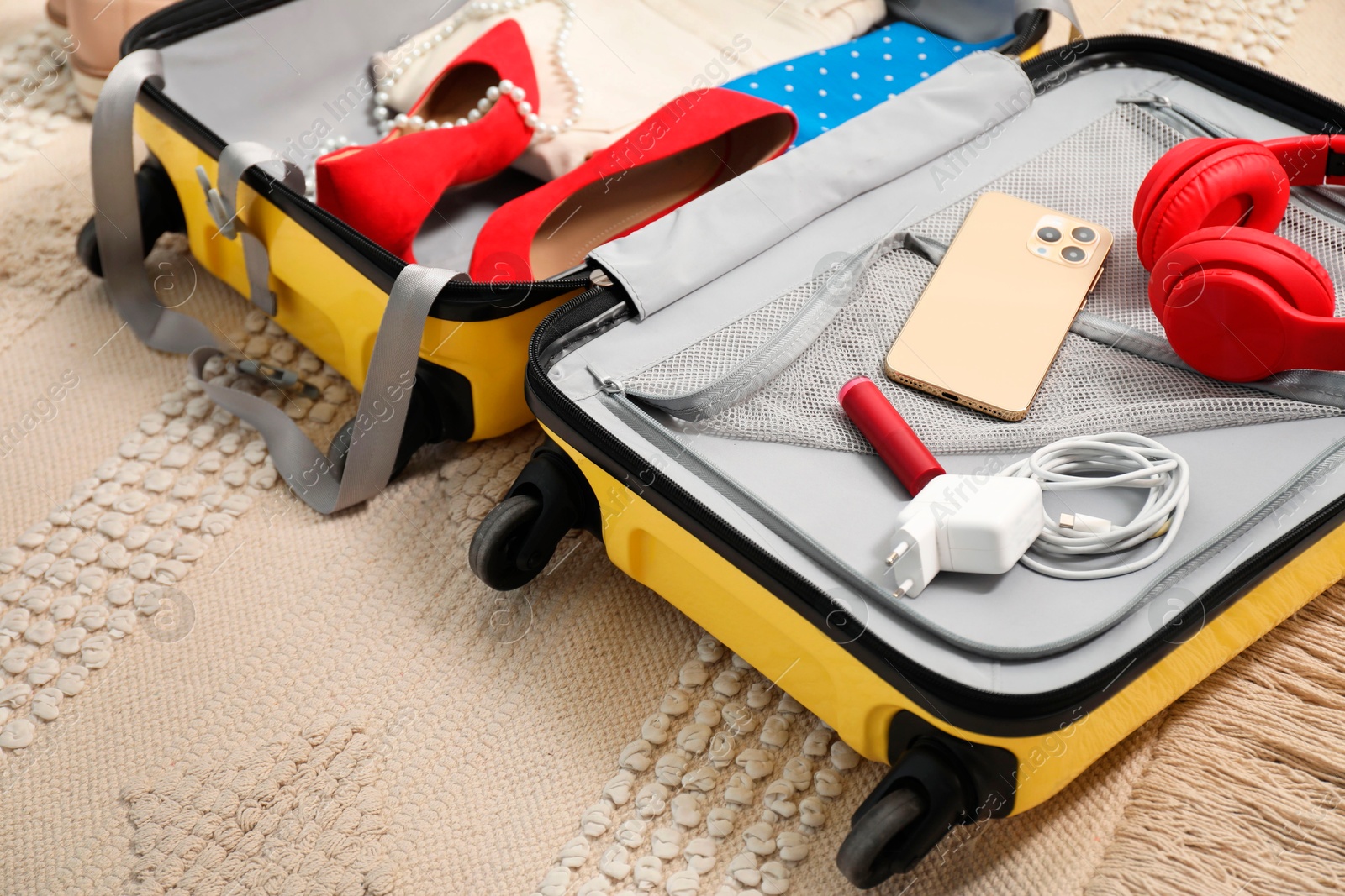 Photo of Open suitcase with traveler's belongings on floor, closeup