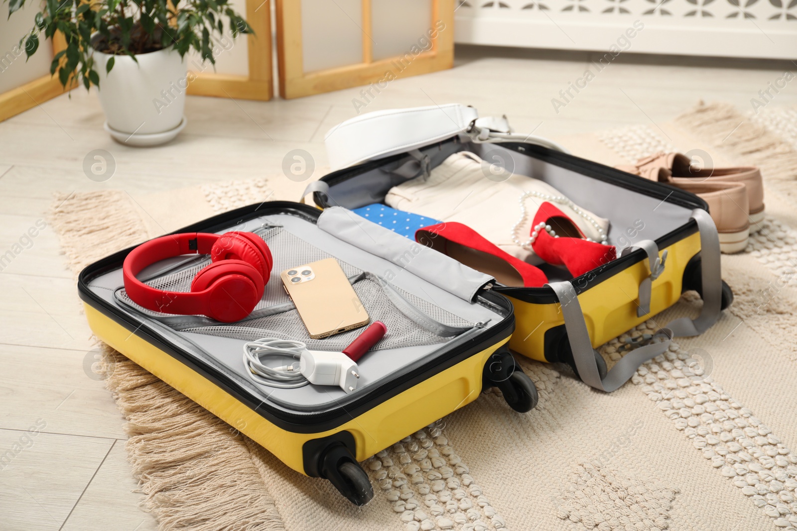 Photo of Open suitcase with traveler's belongings on floor