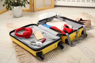 Photo of Open suitcase with traveler's belongings on floor