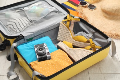 Open suitcase with traveler's belongings on floor, closeup