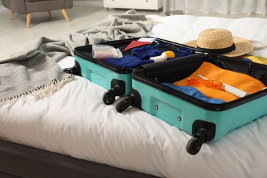 Photo of Open suitcase with traveler's belongings on bed