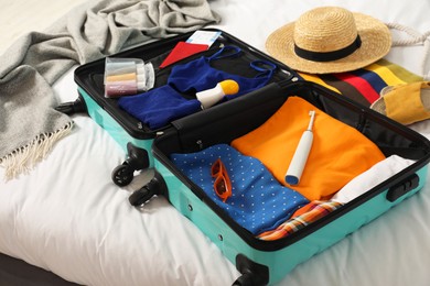 Photo of Open suitcase with traveler's belongings on bed