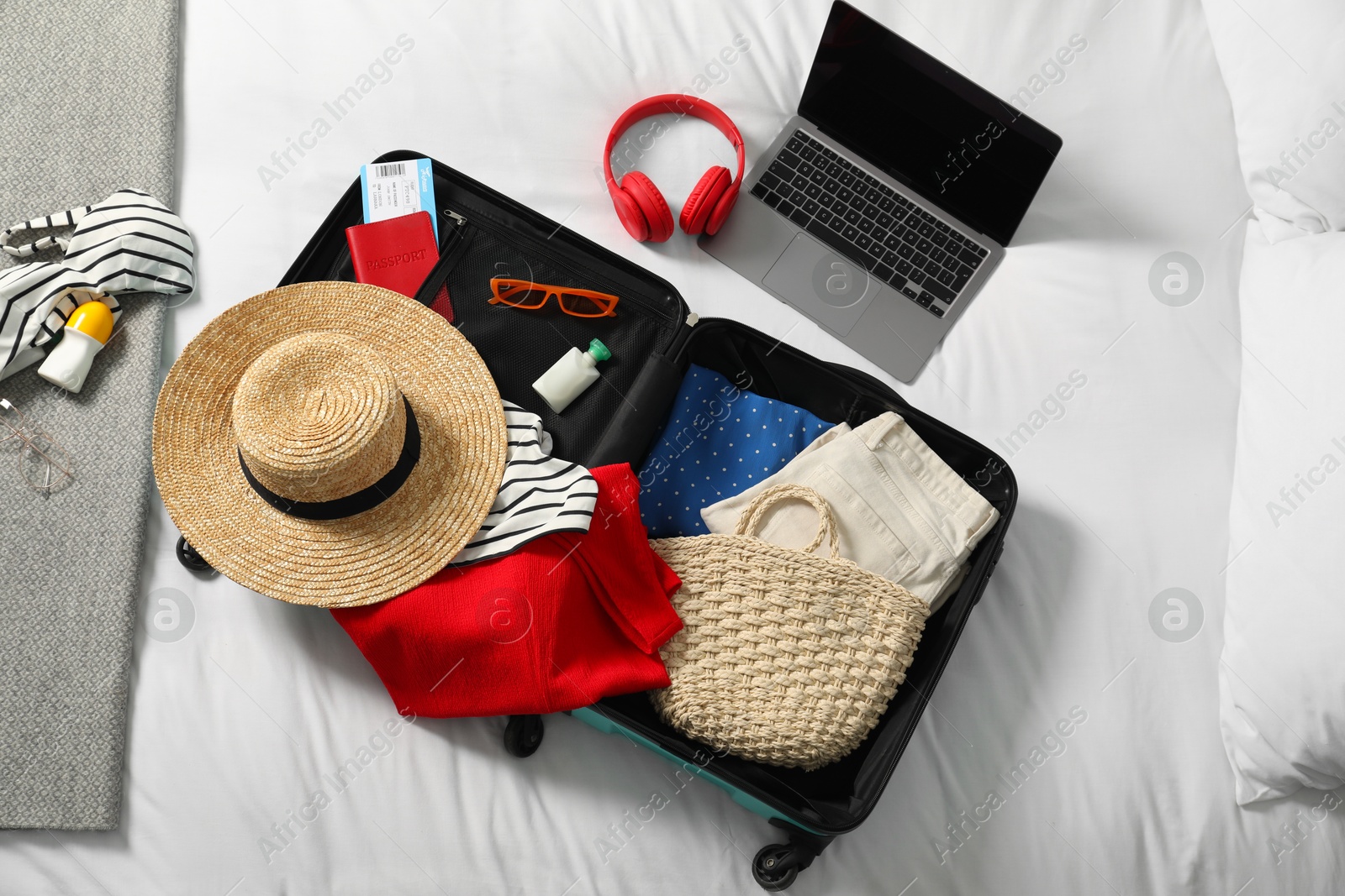 Photo of Open suitcase with traveler's belongings on bed, flat lay