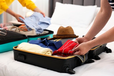 Couple packing suitcases for trip in bedroom, closeup