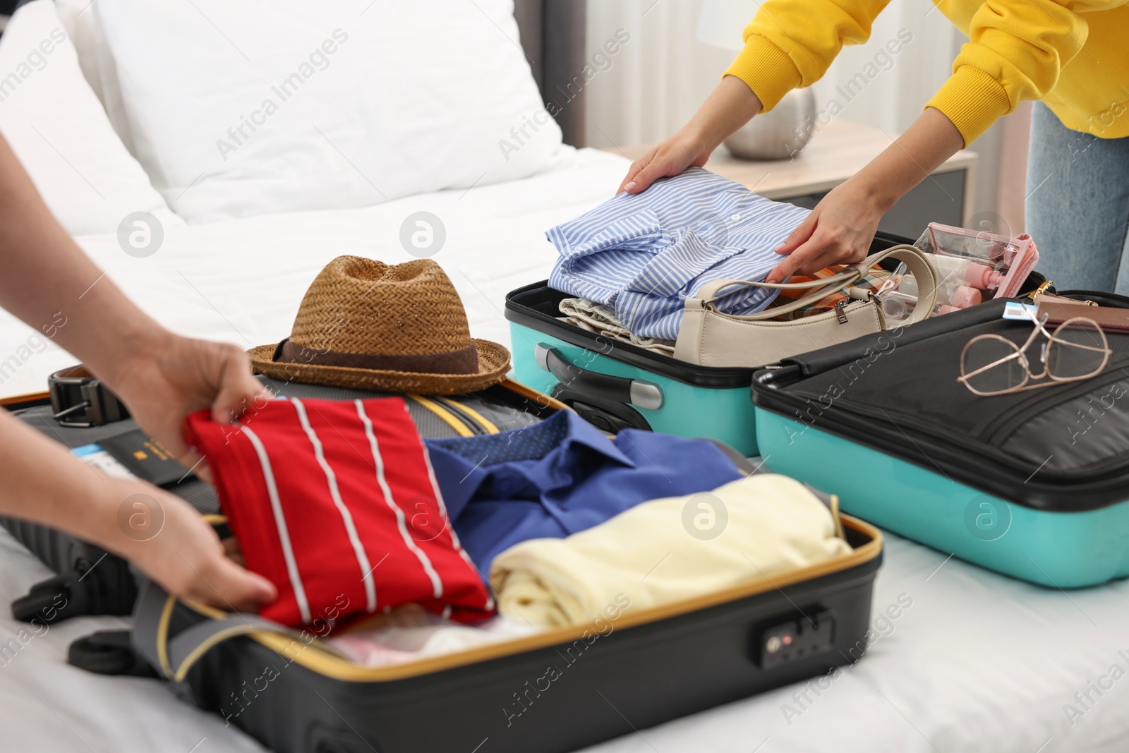 Photo of Couple packing suitcases for trip in bedroom, closeup