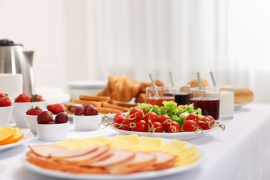 Different meals served on white table indoors, selective focus. Buffet menu