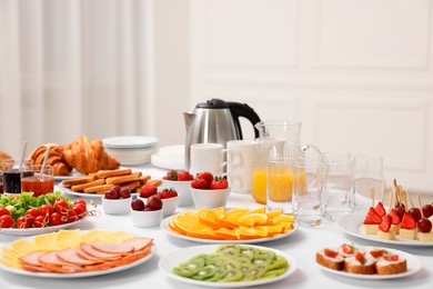 Different meals served on white table indoors. Buffet menu