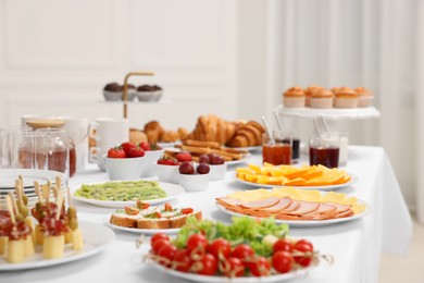 Photo of Different meals served on white table indoors, selective focus. Buffet menu