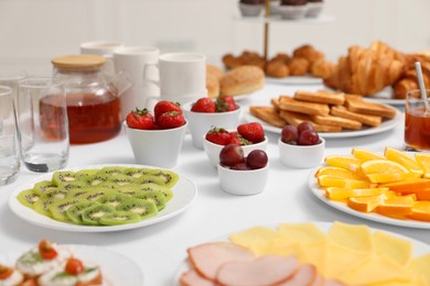 Different meals served on white table indoors, selective focus. Buffet menu