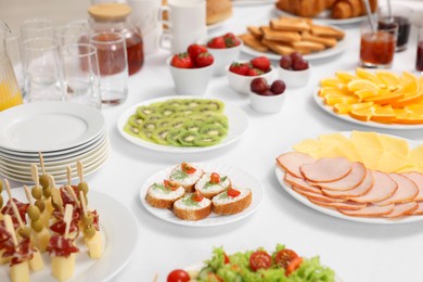 Different meals served on white table indoors. Buffet menu