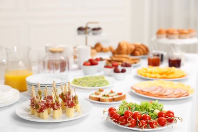 Different meals served on white table indoors. Buffet menu