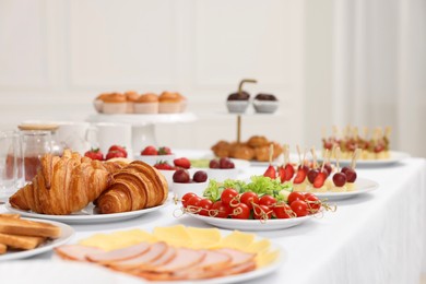 Different meals served on white table indoors, selective focus. Buffet menu