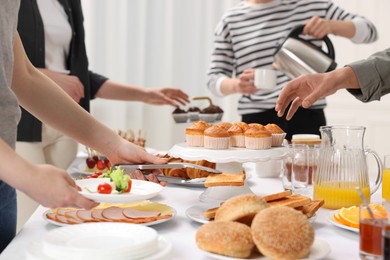 Coworkers having business lunch at white table indoors, closeup