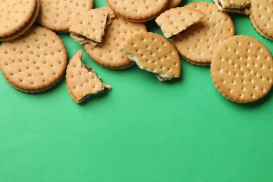 Photo of Tasty sandwich cookies on green background, top view. Space for text