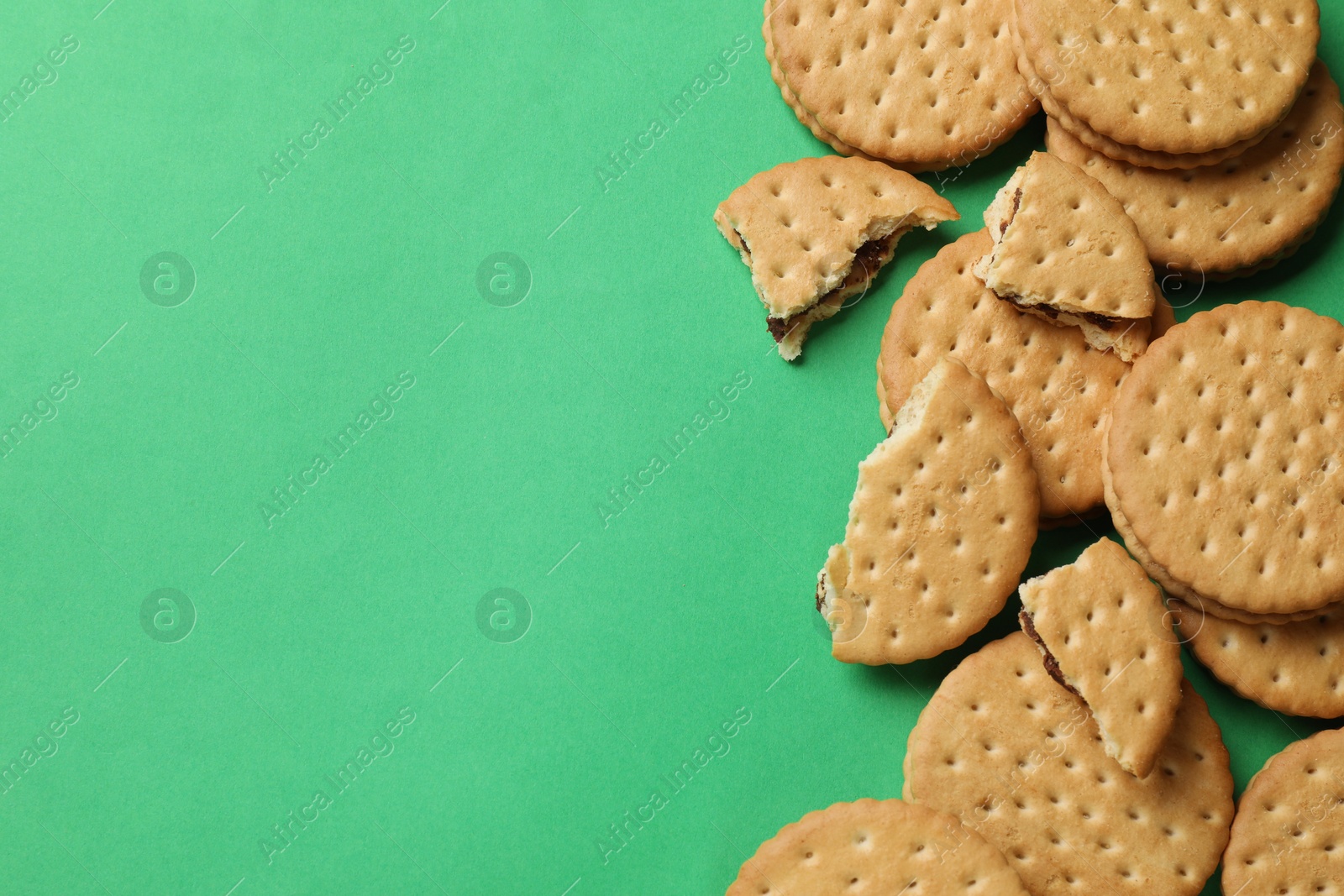 Photo of Tasty sandwich cookies on green background, top view. Space for text