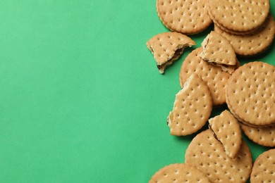 Tasty sandwich cookies on green background, top view. Space for text