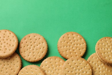 Tasty sandwich cookies on green background, top view. Space for text