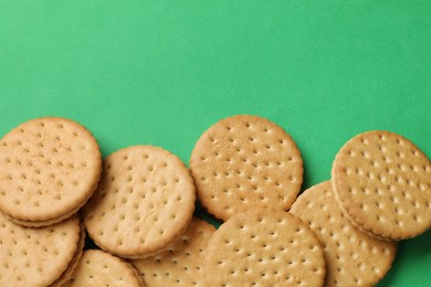 Tasty sandwich cookies on green background, top view. Space for text