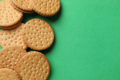 Photo of Tasty sandwich cookies on green background, top view. Space for text